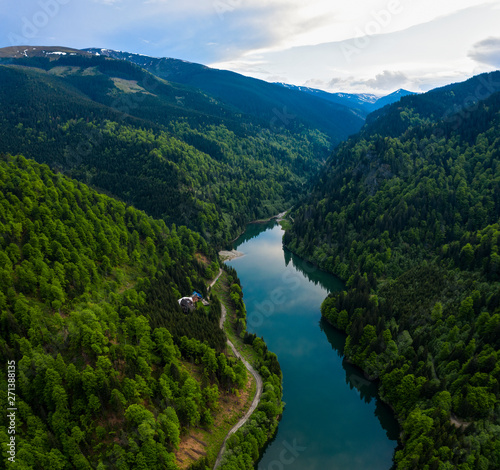 Aerial drone shot of a lake and green forest in Transylvania, Romania