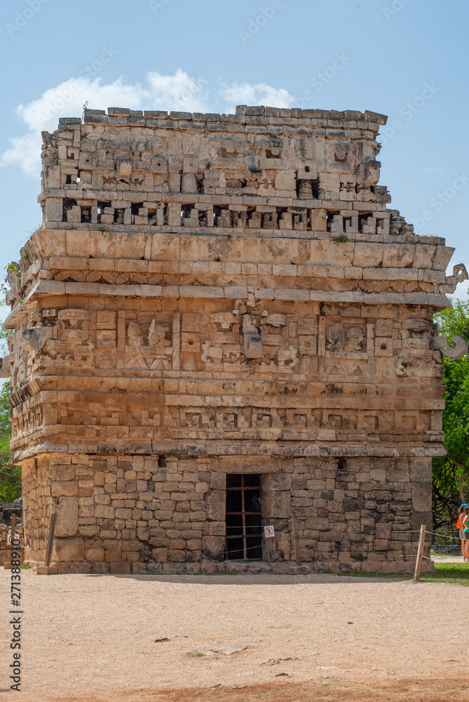 Fototapeta premium Small Mayan temple, adorned with engraved stones, in the archaeological area of Chichen Itza, on the Yucatan peninsula