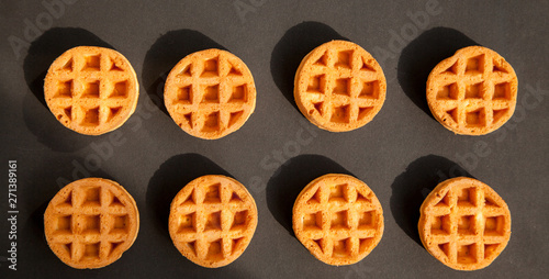 round little Viennese waffles on a black background top view. Sweet background