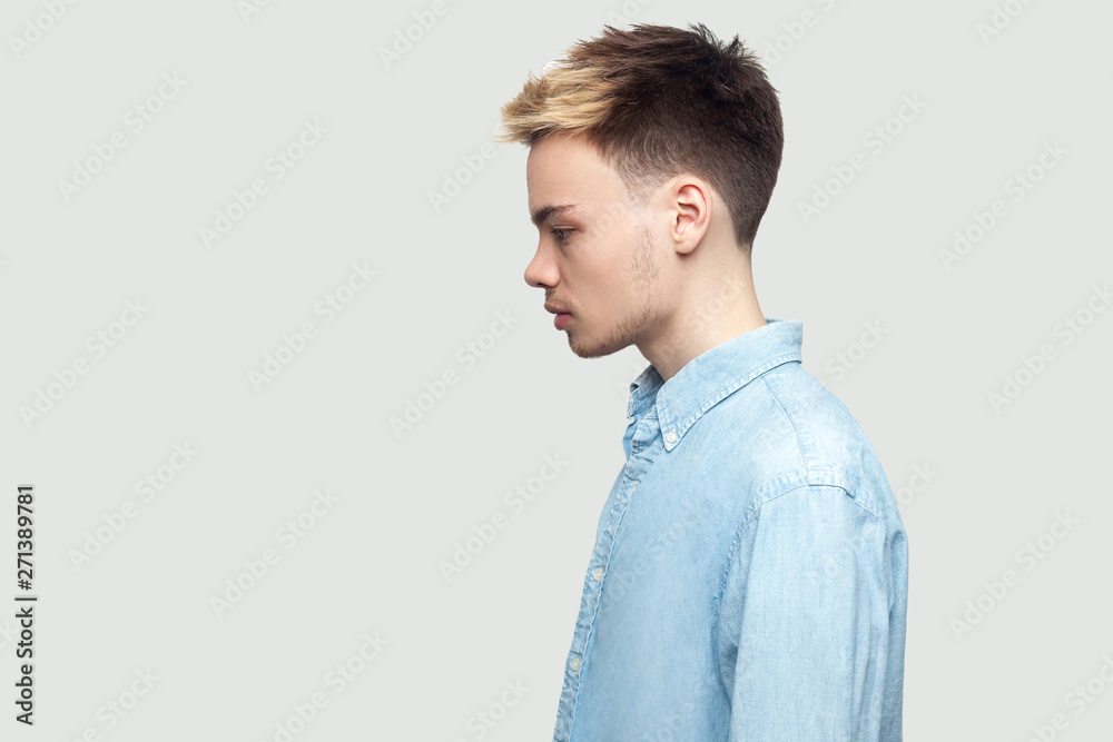 Profile side view portrait of calm serious handsome young man in light blue shirt standing and looking forward with serious face. indoor studio shot on grey background copy space. Profile side view portrait of calm serious handsome young man in light blue shirt standing and looking forward with serious face. indoor studio shot on grey background copy space.