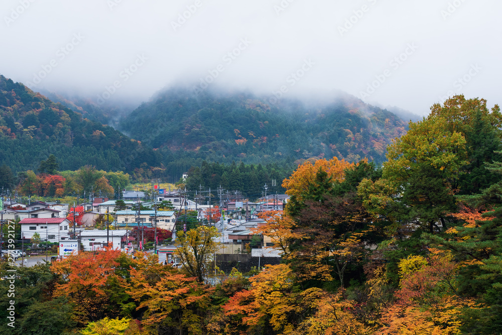 Morning scenery of village surrounded with colorful autumnal trees in Japan