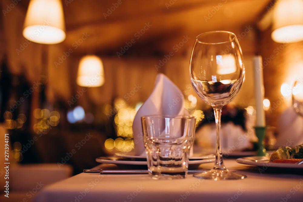 Beautiful decorated elegant wedding table for dinner with floral white bouquets, candlesticks and a white tablecloth glasses and porcelain plates Beautiful decorated elegant wedding table for dinner with floral white bouquets, candlesticks and a white tablecloth glasses and porcelain plates