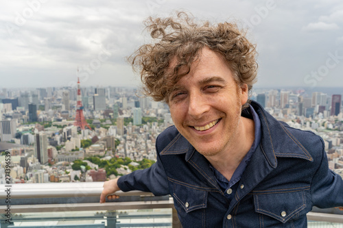 Attractive middle aged man travels in Toyko, Japan and enjoys a beautiful view of the skyline from above.