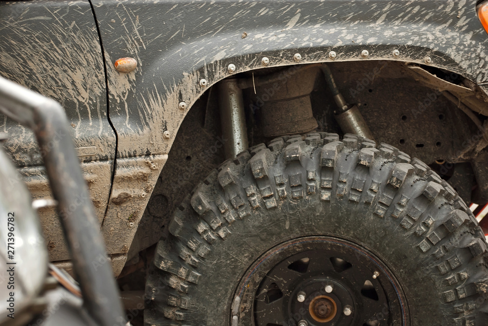 Fototapeta premium Wheels, lights and bumper are laced in a swamp. Dirty truck parts close up.