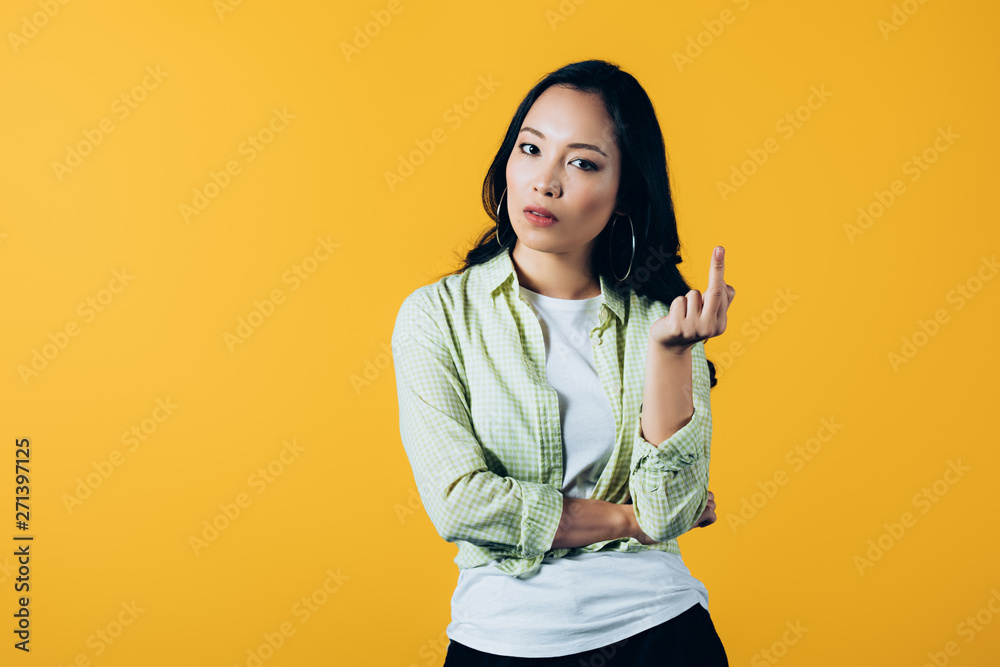 attractive asian girl pointing up isolated on yellow