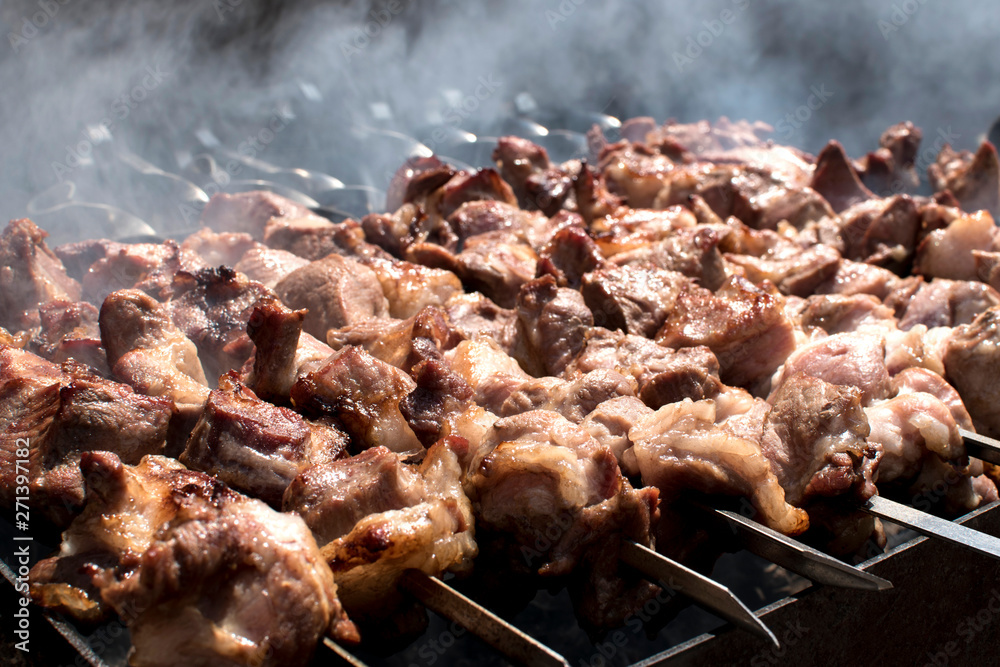 Grilled kebab cooking on metal skewer. Roasted meat cooked at barbecue. BBQ fresh meat chop slices. Traditional eastern dish, shish kebab. Grill on charcoal and flame, picnic, street food Grilled kebab cooking on metal skewer. Roasted meat cooked at barbecue. BBQ fresh meat chop slices. Traditional eastern dish, shish kebab. Grill on charcoal and flame, picnic, street food