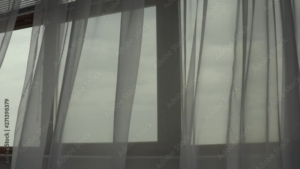 Moving grey transparent curtains at wide window. Filmed with drone