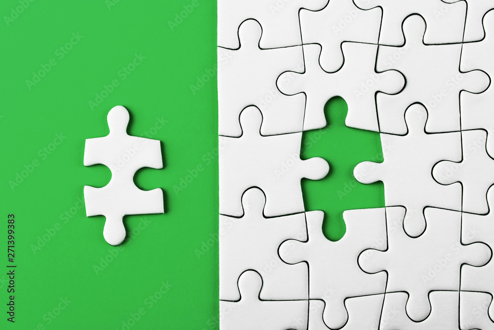 Fototapeta premium Closeup of the last piece of puzzle missing on green background