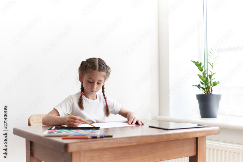 Kid girl drawing and painting at home while sitting at the table Kid girl drawing and painting at home while sitting at the table