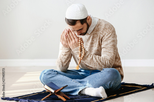 Young Muslim man praying indoors