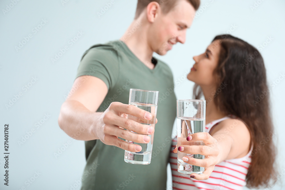 Young couple with glasses of water on light background Young couple with glasses of water on light background