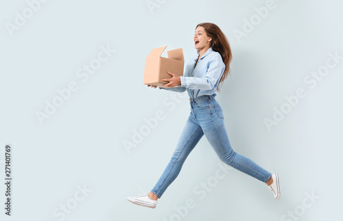 Jumping woman with cardboard box on light background