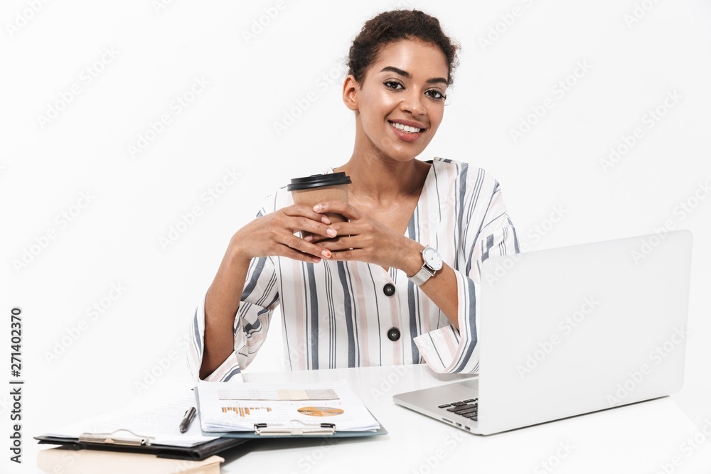 African woman posing isolated over white wall background using laptop computer drinking coffee.