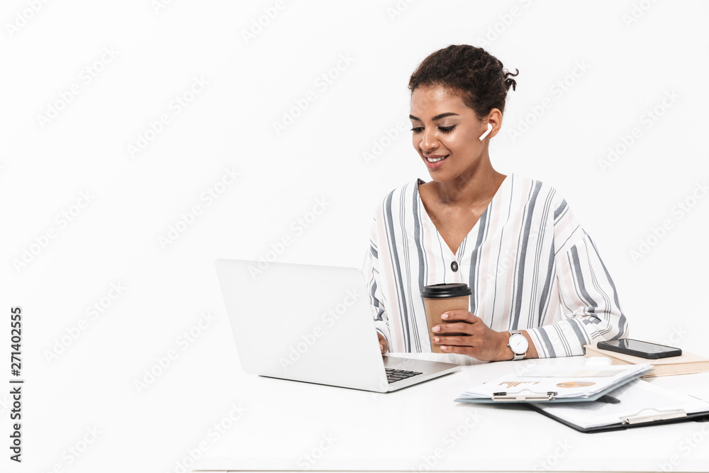 African woman posing isolated over white wall background using laptop computer drinking coffee. African woman posing isolated over white wall background using laptop computer drinking coffee.