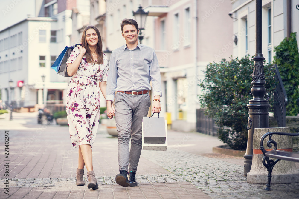 Portrait of happy couple with shopping bags in city smiling and huging.