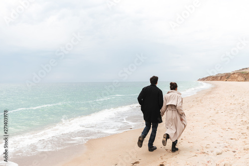 Beautiful young couple wearing coats walking