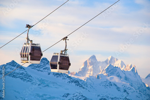 Ski-lift and ski slope in snowy mountains at sunny winter day photo