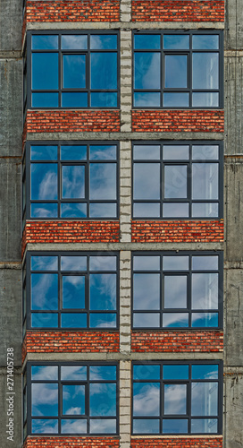 Row of the windowa of apartment building in development state with reflections of blue sky in window glass photo