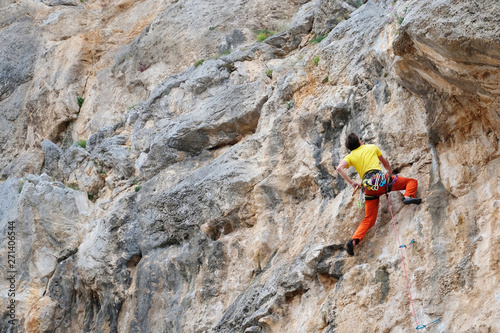 Rock climber reaches the summit. Male rock climber climbs on a rocky wall