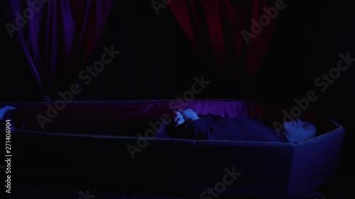 A man in the coffin is scratching his privates, dark blue lighting, 4k