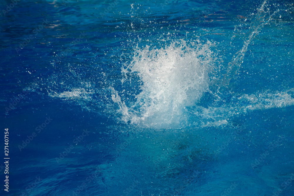 Fototapeta premium Powerful splash on a blue water surface with waves and splashes.