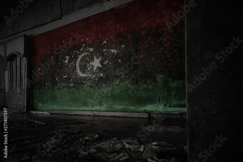 painted flag of libya on the dirty old wall in an abandoned ruined house.