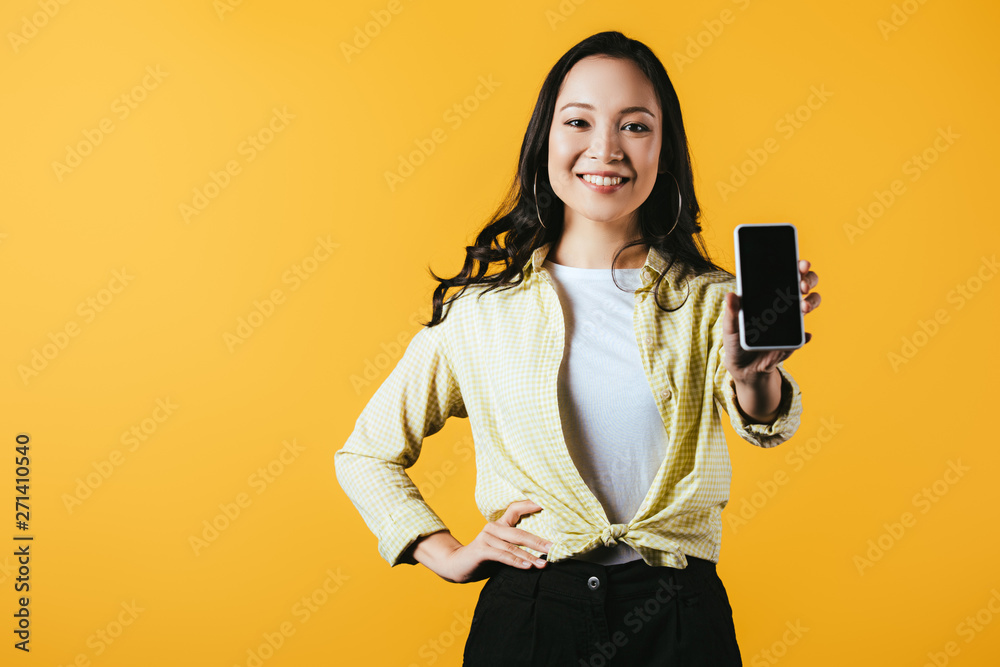attractive asian girl showing smartphone with blank screen isolated on yellow attractive asian girl showing smartphone with blank screen isolated on yellow