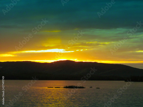 Bright colorful sunset over a lake. Beautiful reflection by a tranquil water of amazing sky and the lakeside at sundown in the summer evening. Lake Elovoe  Spruce Lake   South Ural  Russia.