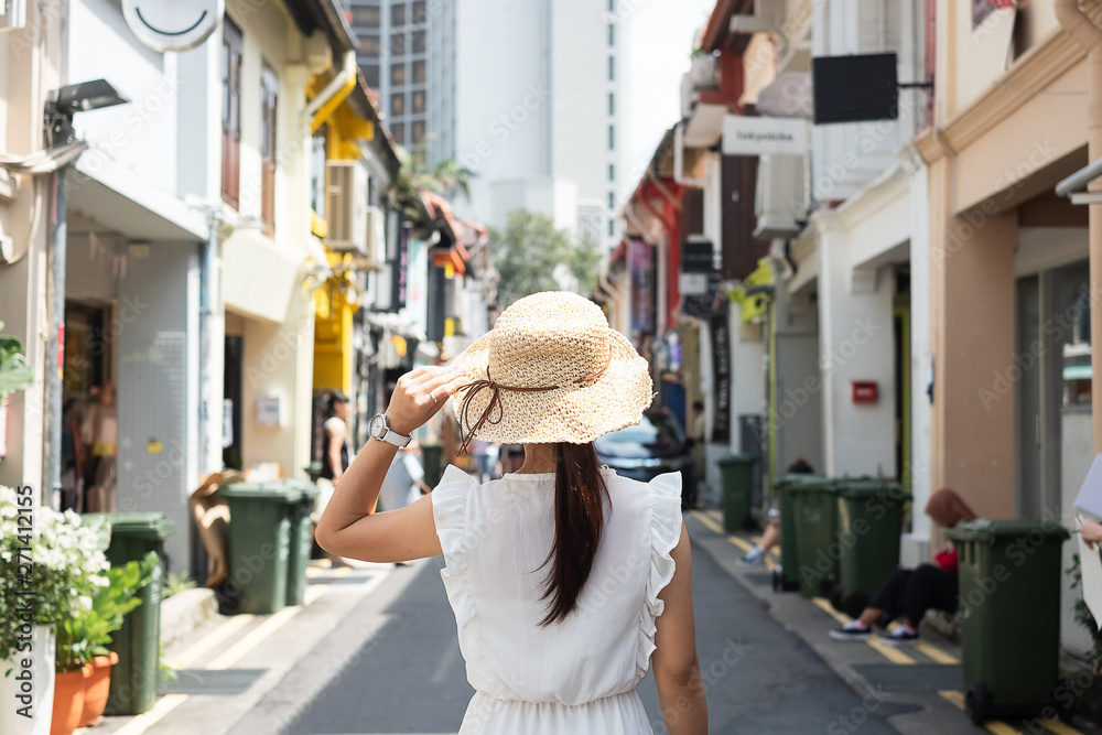 Young woman traveling with white dress and hat, happy Asian traveler walking at Haji Lane and Arab street in Singapore. landmark and popular for tourist attractions. Southeast Asia Travel concept