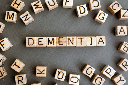 the word dementia wooden cubes with burnt letters, memory loss due to neuronal damage in the brain gray background top view, scattered cubes around random letters
