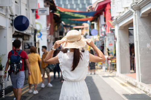 Young woman traveling with white dress and hat, happy Asian traveler walking at Haji Lane and Arab street in Singapore. landmark and popular for tourist attractions. Southeast Asia Travel concept photo