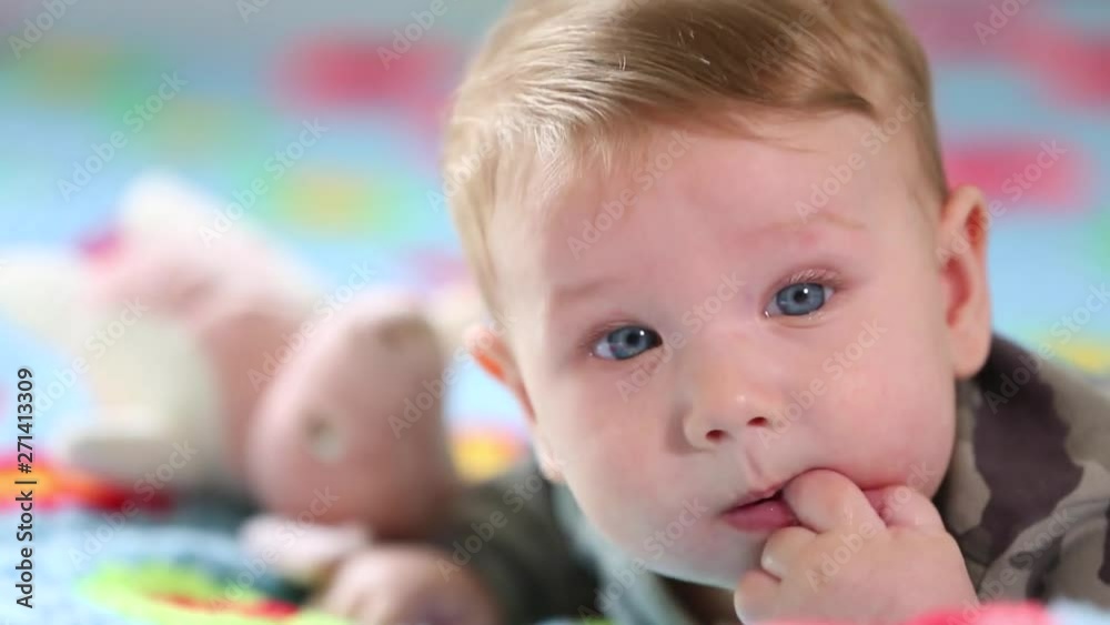 Beautiful Smiling Baby: A gorgeous little baby lies on the bed and smiles at the camera with a nice soft focus background