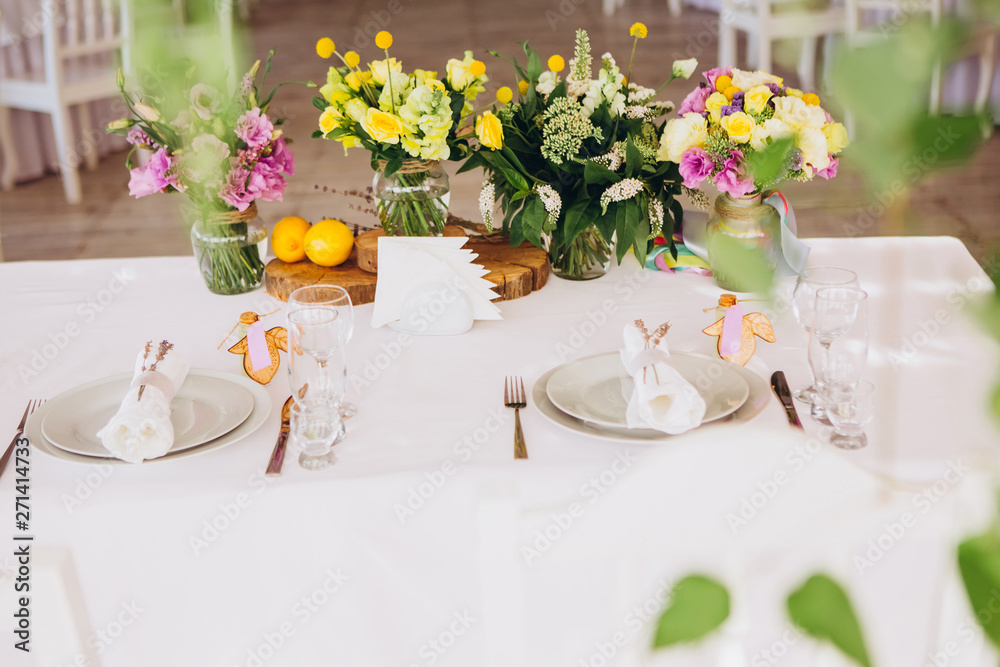 Round white table with elegant compositions from natural flowers. Banquet at the luxury wedding. Elegant design wedding table.
