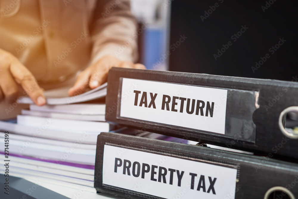Tax return and property tax folders stack with label black binder on paperwork documents summary report in busy offices by manager checking. HR-human resources business bookkeeping accountancy Concept Tax return and property tax folders stack with label black binder on paperwork documents summary report in busy offices by manager checking. HR-human resources business bookkeeping accountancy Concept