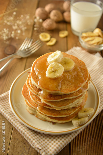 Stack of pancakes with banana slices and honey, on wooden background. Homemade american pancakes, isolated.