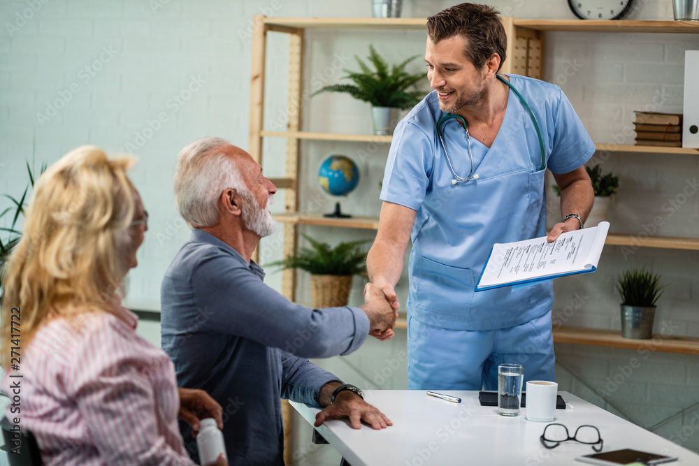 Obraz premium Happy doctor greeting senior couple who came to medical appointment.