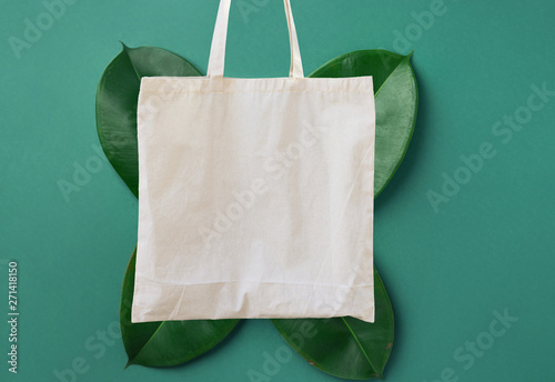 Blank white mockup linen cotton tote bag on green leaves foliage background. Zero waste reusable nature friendly materials. Environmental conservation recycling plastic free concept photo