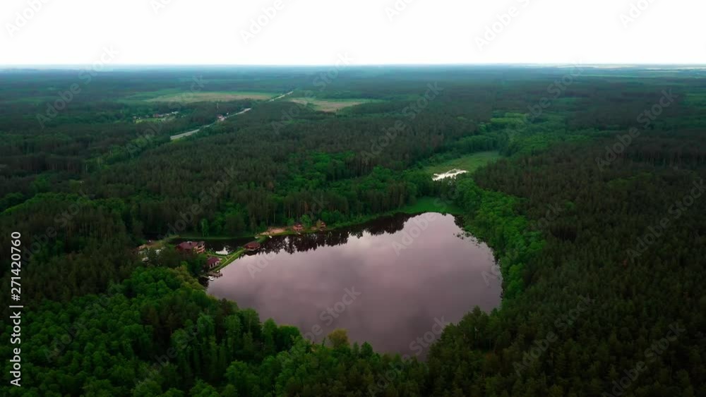 4K Arial Drone shot. Birds eye view of a lake surrounded by a lush green forest. 4K Arial Drone shot. Birds eye view of a lake surrounded by a lush green forest.