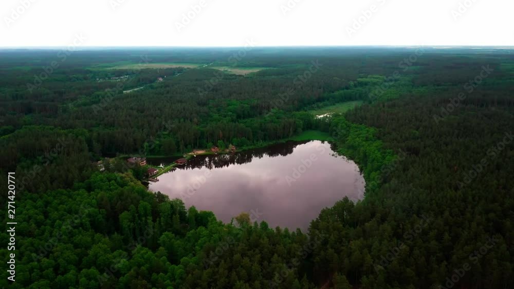 4K Arial Drone shot. Birds eye view of a lake surrounded by a lush green forest. 4K Arial Drone shot. Birds eye view of a lake surrounded by a lush green forest.