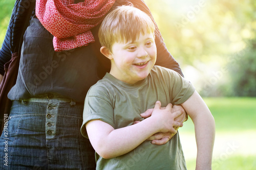 Quadro su tela Little boy with down syndrome cuddling up to his mother in a park