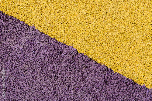 Protective yellow-purple rubber crumb coating. The texture is a safe rubberized surface for playgrounds and sports fields. Close up