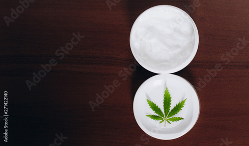 Moisturizing hemp hand cream in dose with green cannabis leaf. Cannabis cosmetics. Cream from biological and ecological plants of hemp vegetable pharmaceutical oil CBD