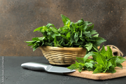 Mint. Leaves and branches of fresh green wild mint on a cutting board on a black concrete table.