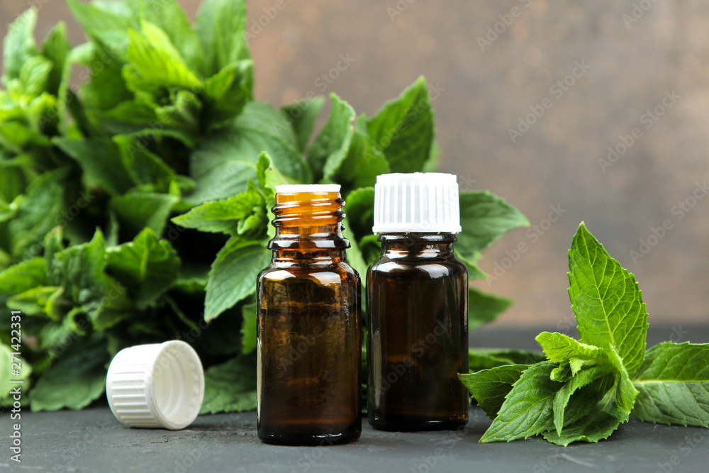mint aroma oils and leaves and branches of fresh green wild mint on a black concrete table. close-up mint aroma oils and leaves and branches of fresh green wild mint on a black concrete table. close-up