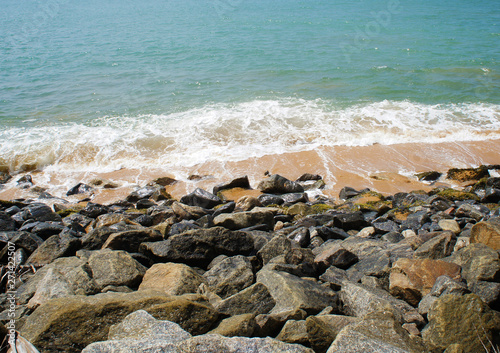 Southern tropical summer ocean coast with rocks and rocks. Lagoon with a yellow sandy beach and azure water.