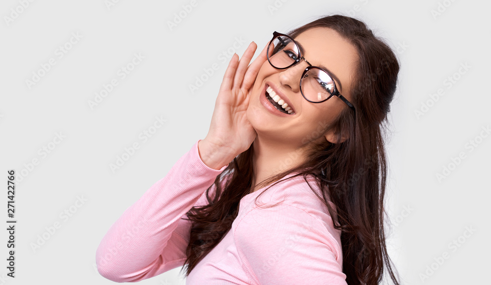 Pretty positive European young woman in pink long sleeve blouse and round transparent eyewear, smiling broadly, isolated over white background. People real emotions Pretty positive European young woman in pink long sleeve blouse and round transparent eyewear, smiling broadly, isolated over white background. People real emotions