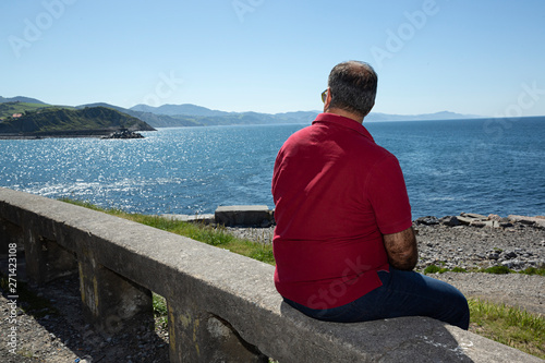 Hombre maduro sentado mirando el mar.