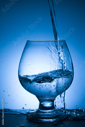 glass of water with splash on blue background