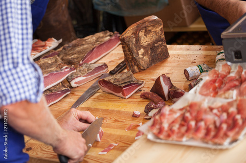 VAL DI FUNES, ITALY - OCTOBER 01, 2016: Traditional smoked speck sliced on site during the "Speckfest" celebration in Val di Funes, Dolomites.