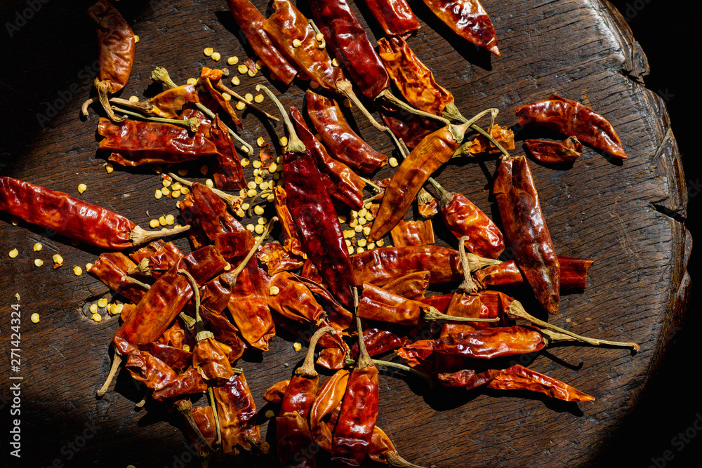 Whole dried chilli peppers with seeds lying in sunlight beam